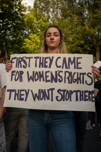 a woman holding a sign while standing next to other people