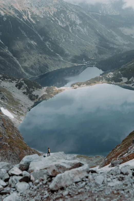 a man standing in front of a lake next to a mountain