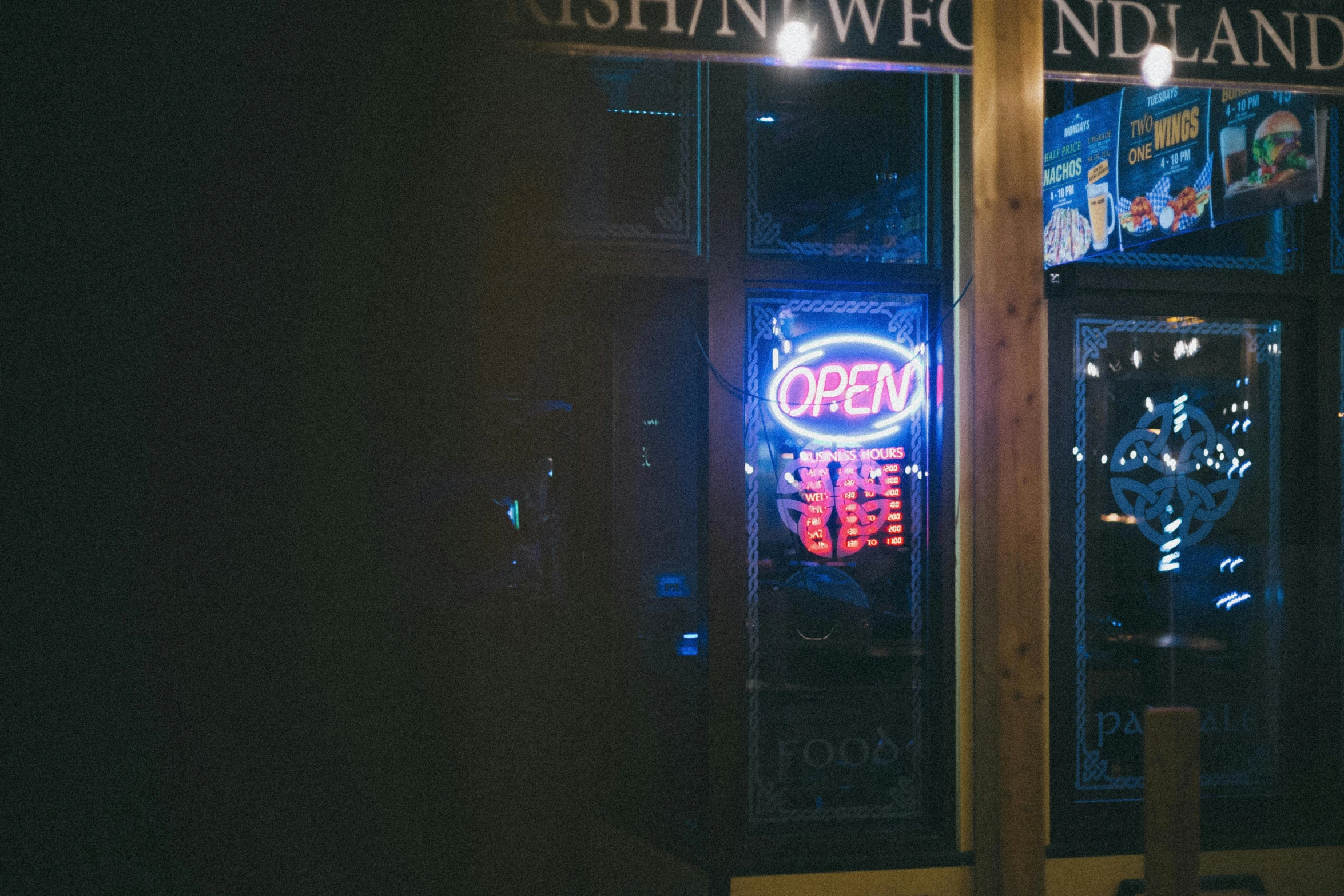 a neon sign inside of a restaurant with two large windows