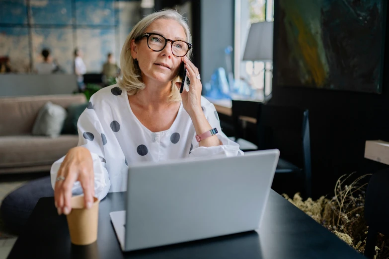 woman sitting at table with coffee looking into laptop