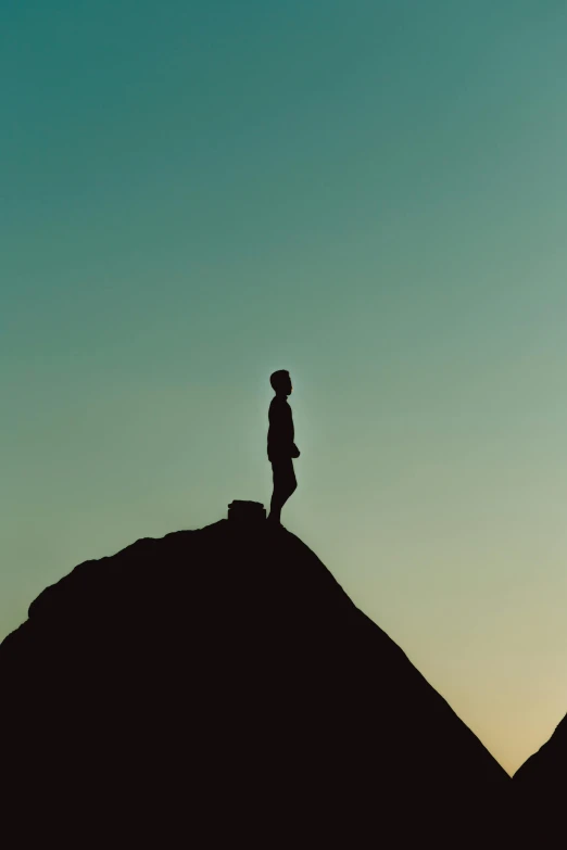 a silhouette of a person standing on top of a mountain