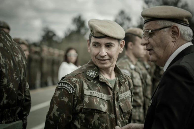 an older man in military attire is talking to another old man