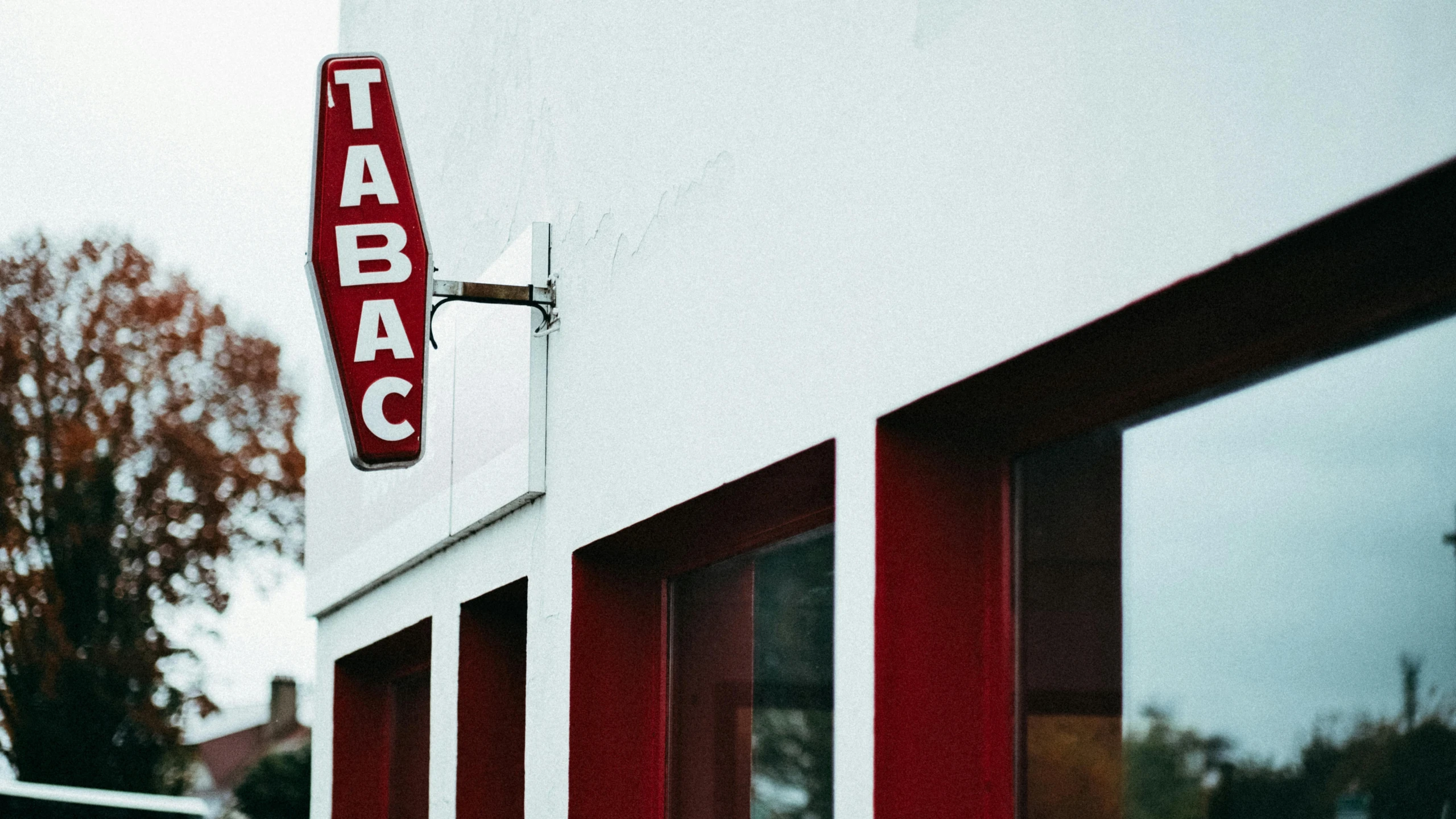 a red sign hangs on the side of a white building