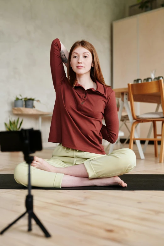 a girl sitting on the floor and posing with her hand in the air