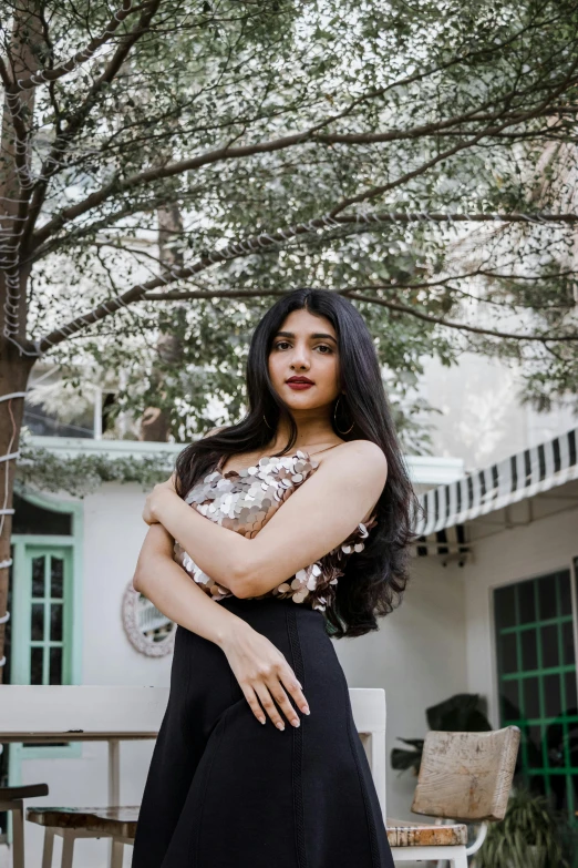 a woman wearing black dress posing in front of a tree