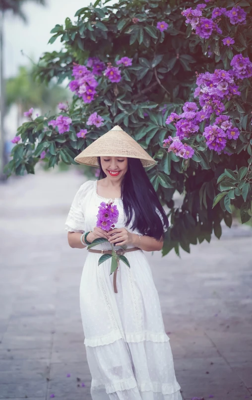 a woman is holding a bunch of flowers and standing next to some purple flowers