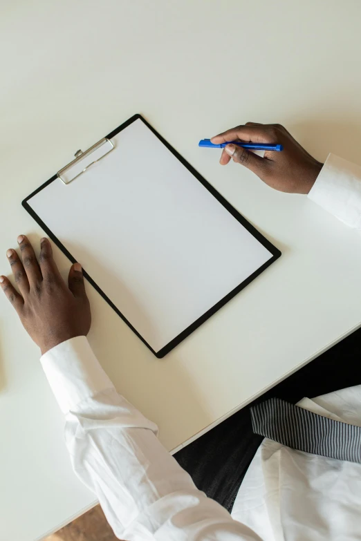 a hand is drawing on a clipboard next to an office phone