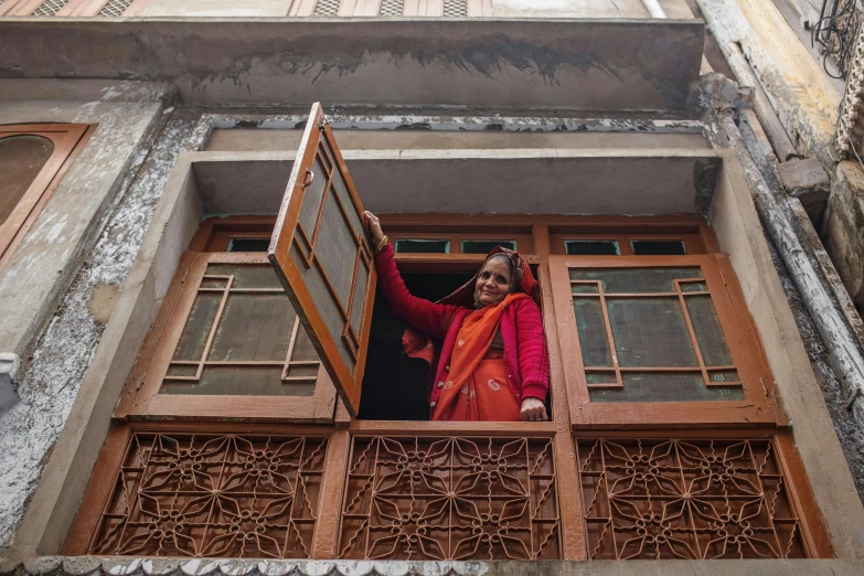 a woman is looking out a window while wearing a red jacket