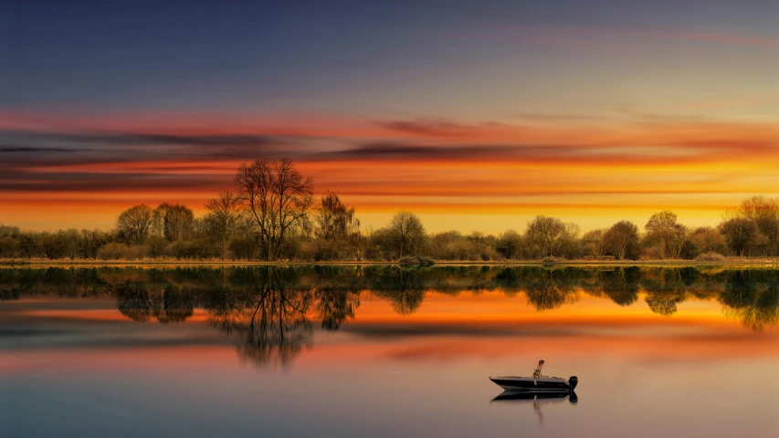 a small boat floating on top of a body of water under a sunset