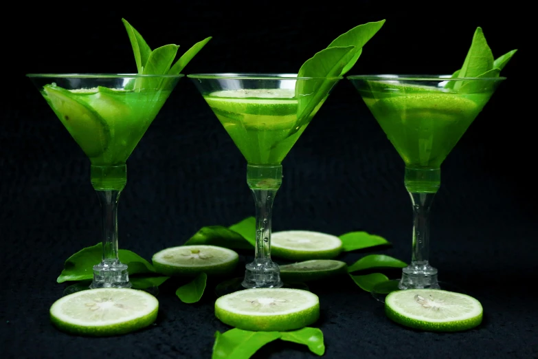 a group of four green beverages filled with liquid