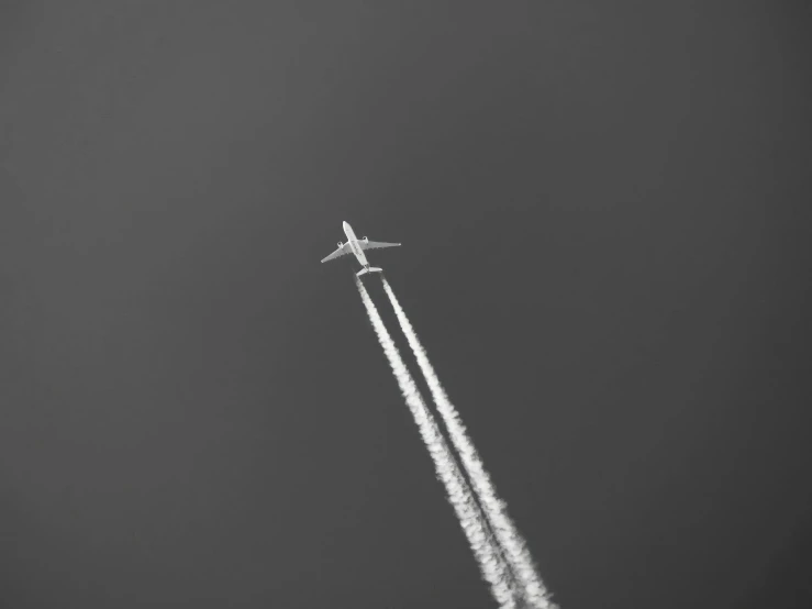 an airplane flying in the air leaving a trail