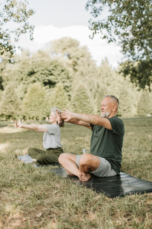 an old man and woman are doing yoga outdoors