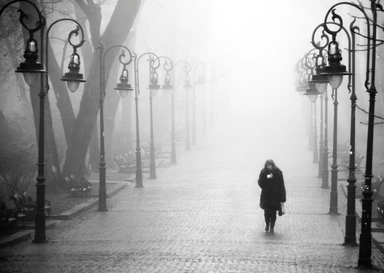 a woman walks alone during a foggy city day