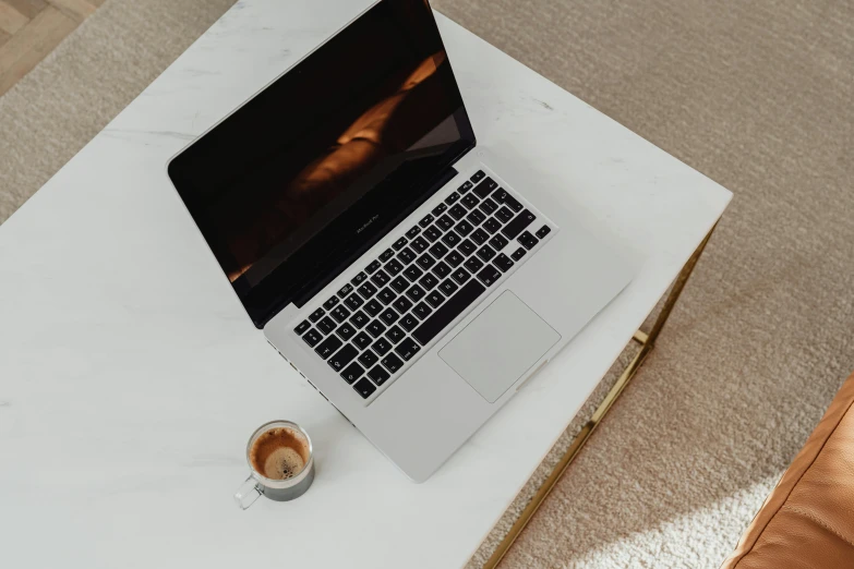 an open laptop on a marble desk with a coffee cup