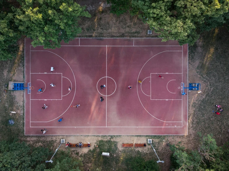 people playing basketball on an overhead court in a forest