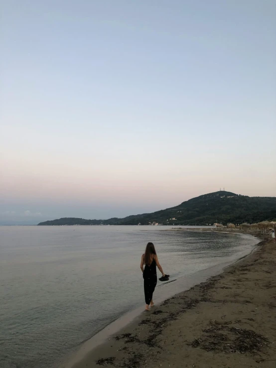 a woman in black and red jumpsuit standing by the beach