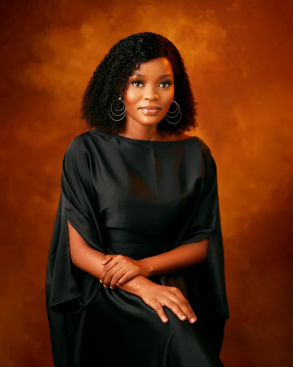 a woman sitting down wearing a black dress