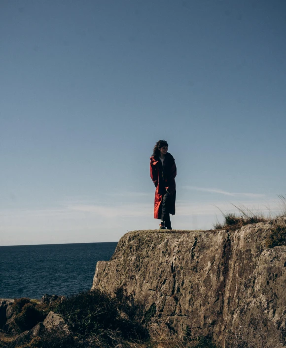 a person standing on a cliff by the ocean