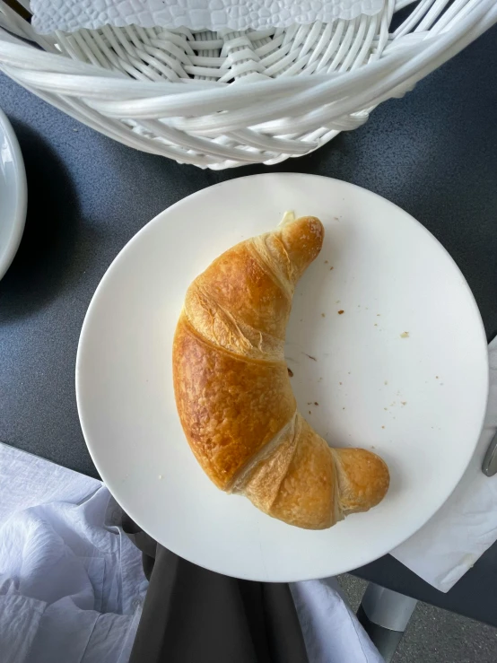 there is a croissant on the plate beside a cup