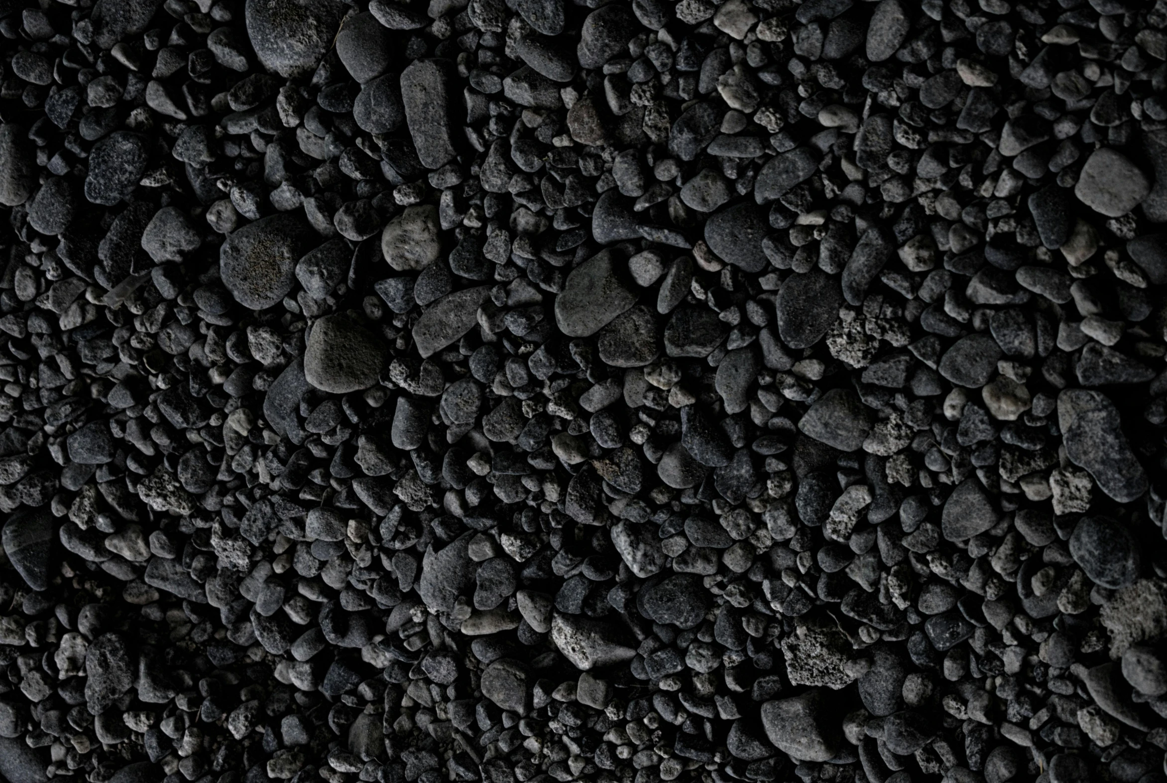 a black rock wall is shown with rocks scattered around it