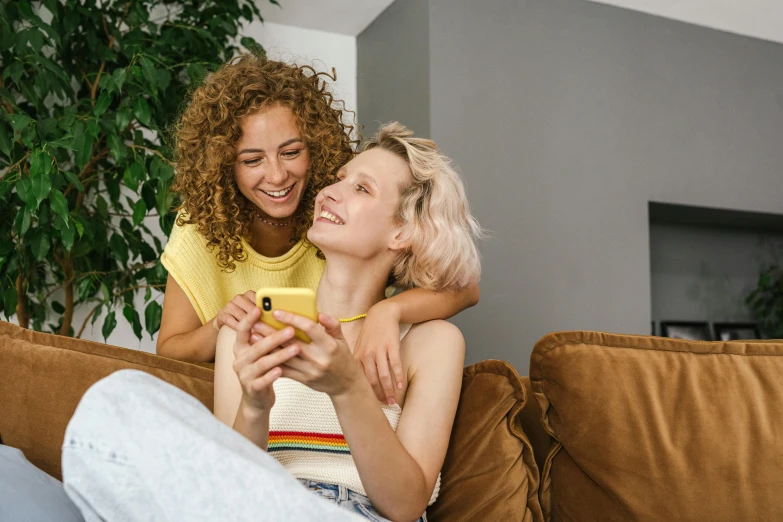 two people sitting on a couch and one woman holds a banana