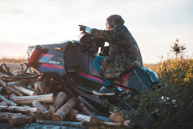 a man riding a snowmobile on a pile of logs