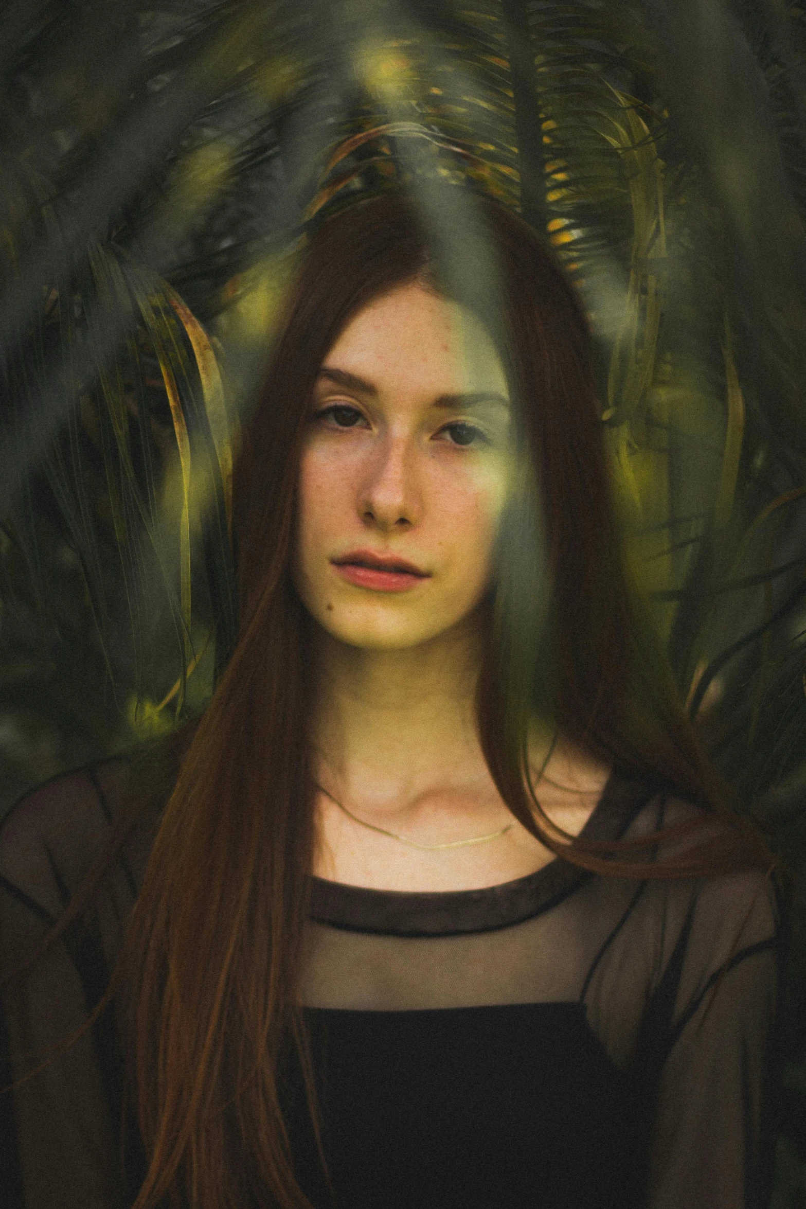 a woman with long hair stands in front of a forest