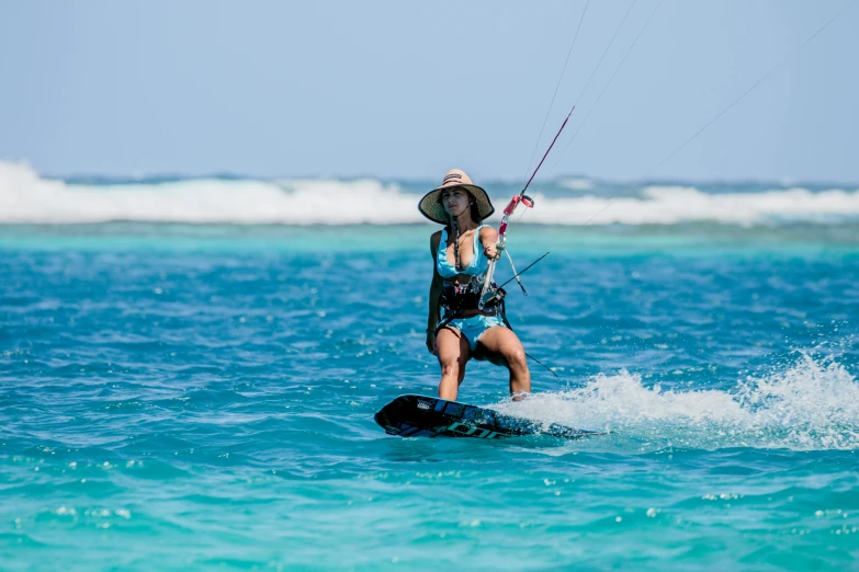 a woman in a hat waterskiing at the beach