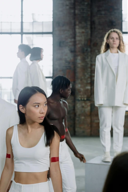 models stand on white cubes in front of a brick wall