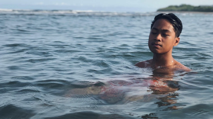 a young man with an object swimming in the ocean