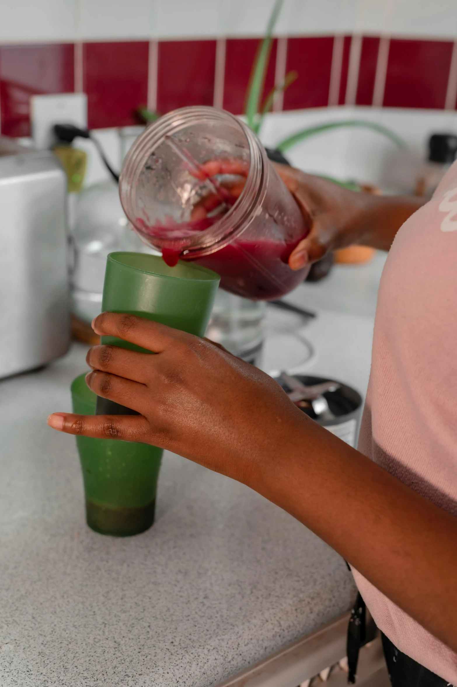 a person with pink shirt and green cup on a counter