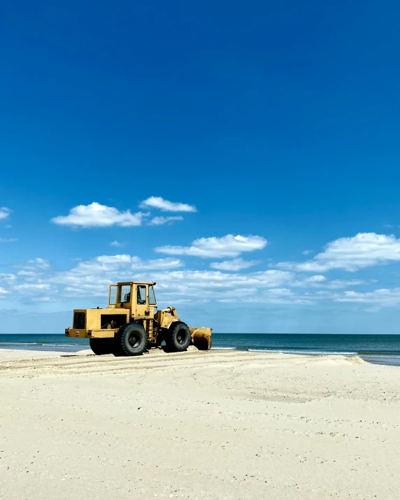 a large construction vehicle on a beach next to the ocean