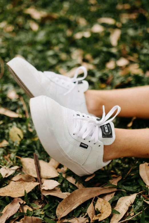 a close up of a person's legs with white shoes