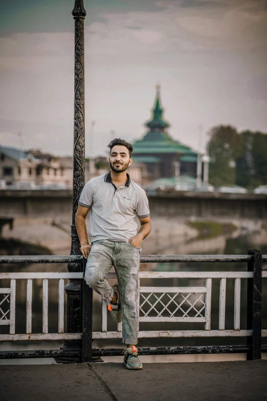 a man leaning against a metal railing on a bridge