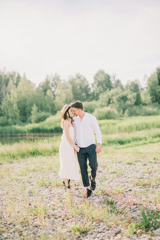 an engaged couple walk through a rocky field in front of a forest