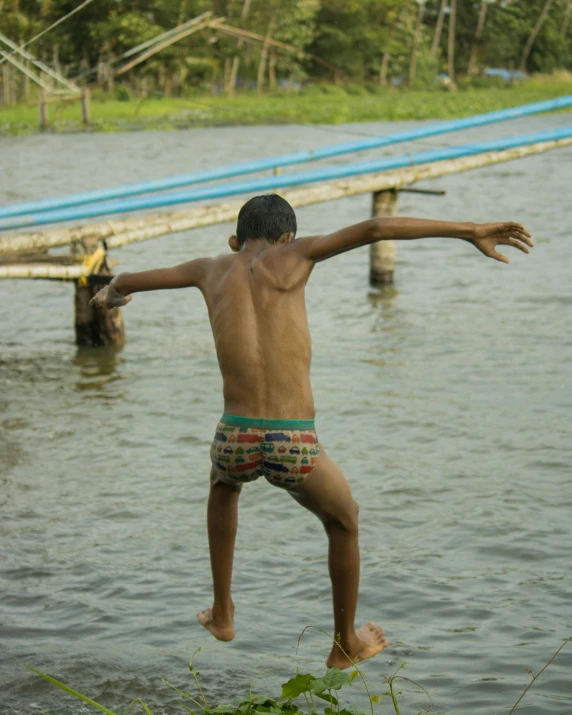 a boy jumping into the water at the edge of a dock