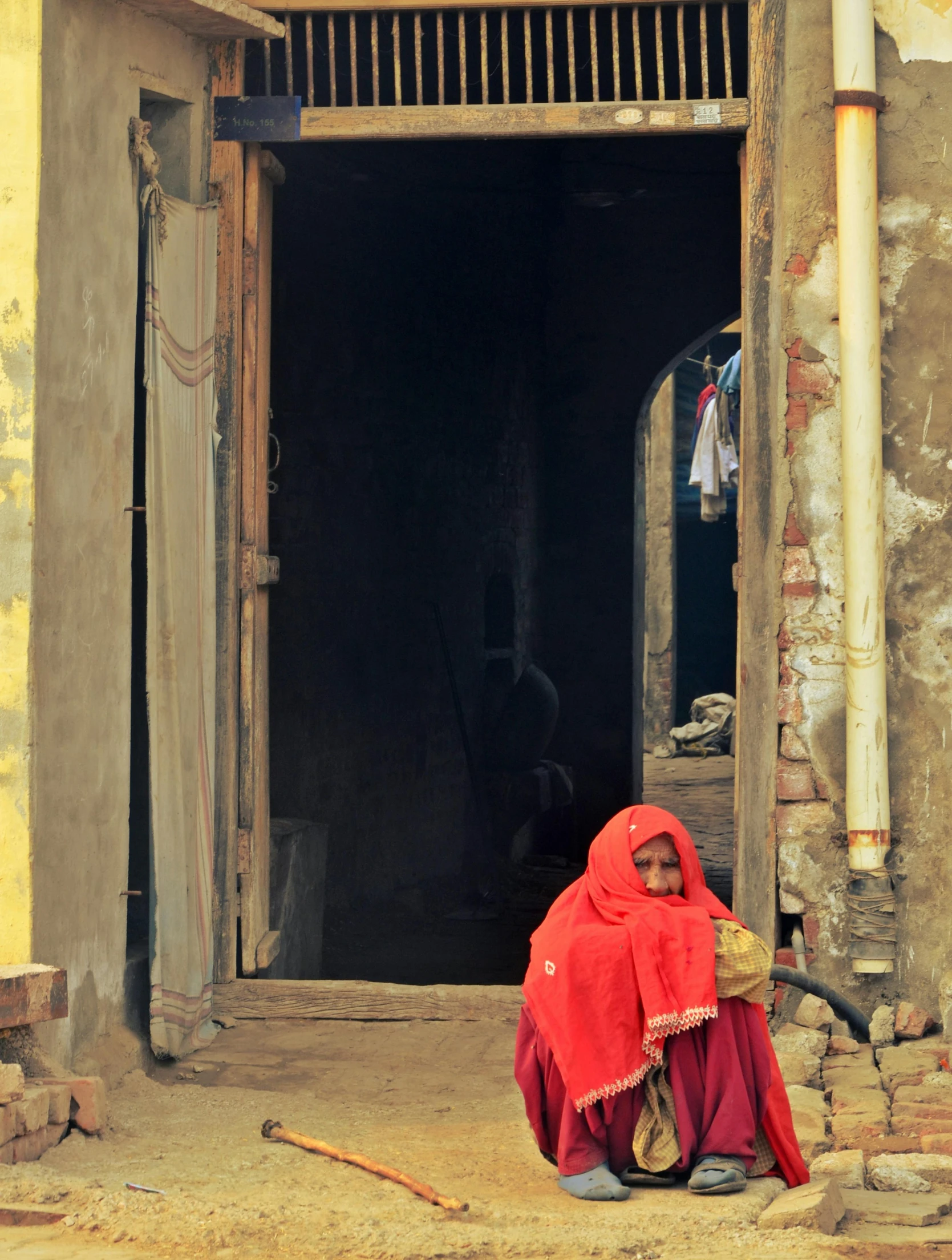 a  sitting outside a door wearing a red scarf