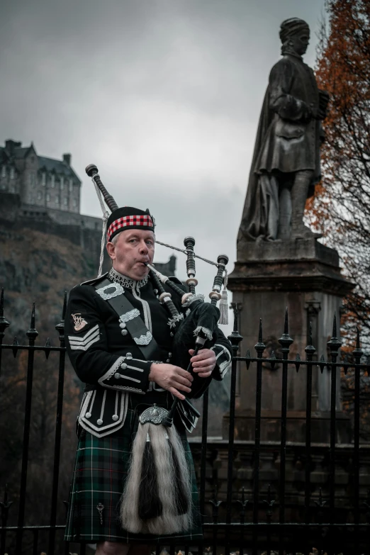 a bagpiper in uniform stands at the gate