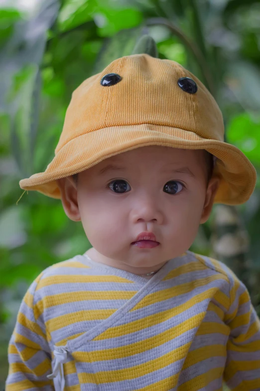 a little boy wearing a yellow hat on top of his head