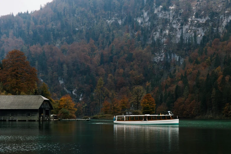 a house boat on the lake is floating past trees