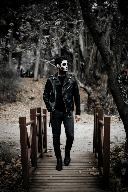 man wearing a black and white face paint walking on a path