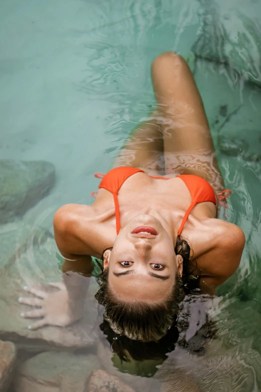 a woman in an orange bikini swims in the water