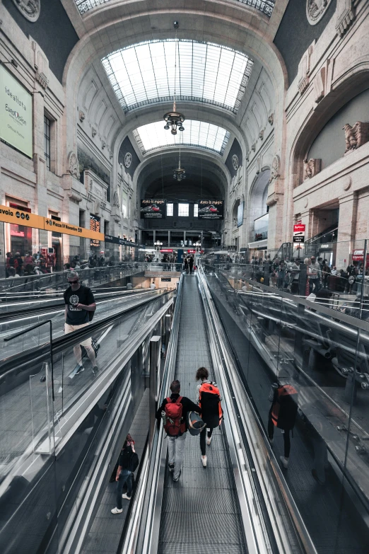 people walk through an empty train station on their luggage