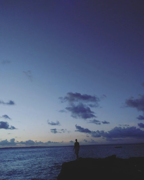 person looking at the ocean while standing on the edge of a cliff