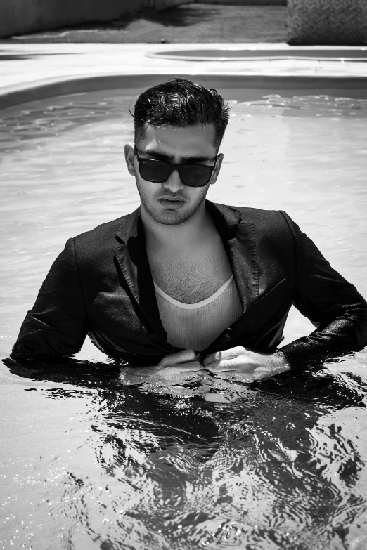 a man in sunglasses and blazer standing in water