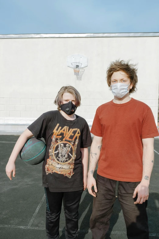 a couple of men holding basketballs in a parking lot