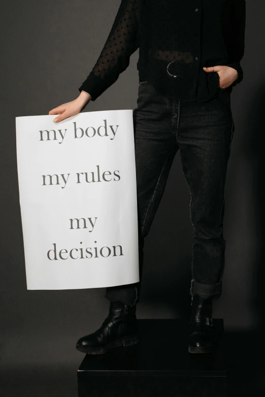 a woman holds a sign in front of her face while posing for the camera