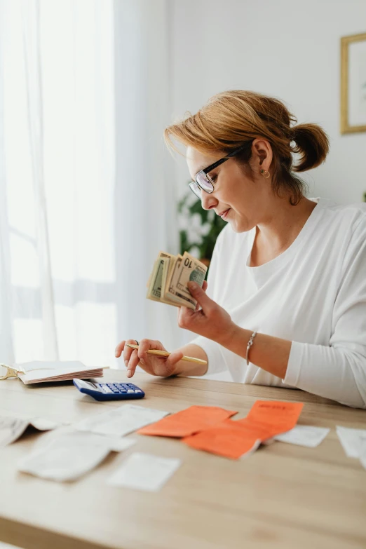 a woman holding money and using a calculator