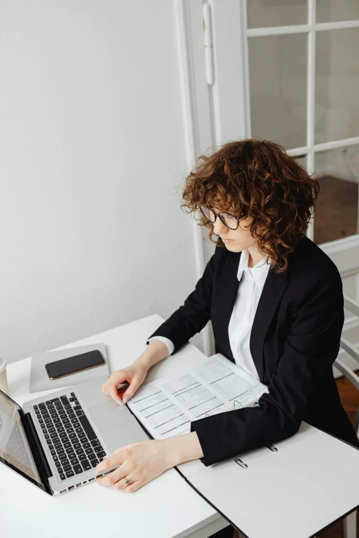 a person is sitting at a white table with a laptop