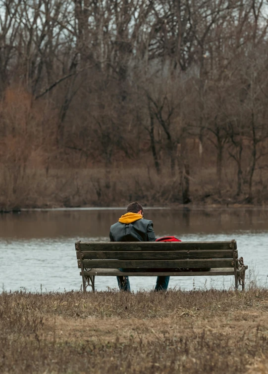 an image of a person sitting on a bench near the water